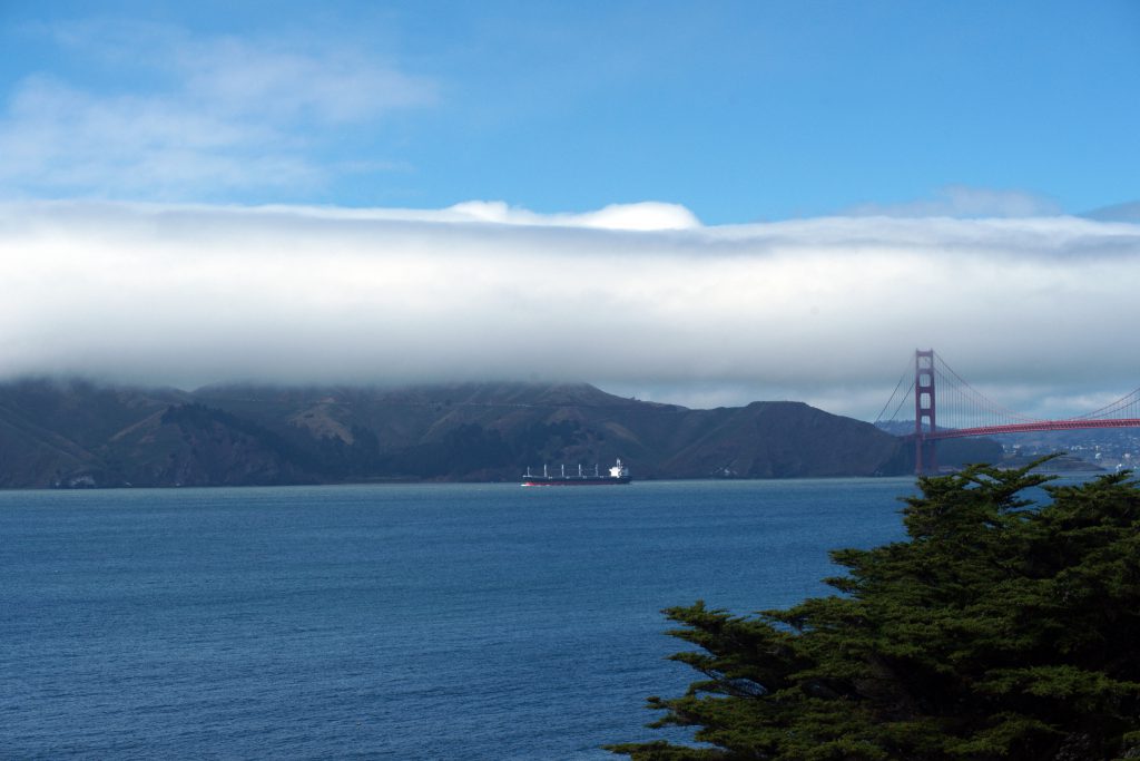 View of the headlands and golden gate bridge with a container ship in the bay.
