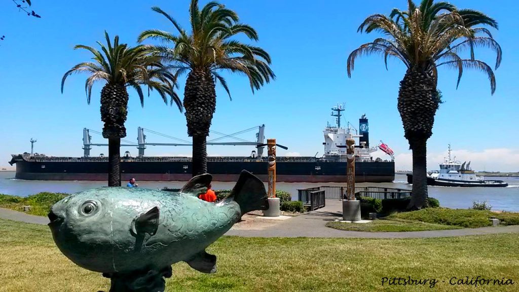 Sculpture of a fish and totem poles along the Pittsburg, California waterfront.