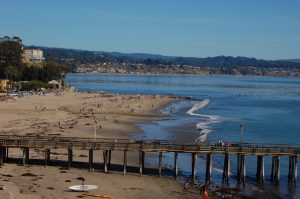 A beach and pier in Capitola with people enjoying the day.