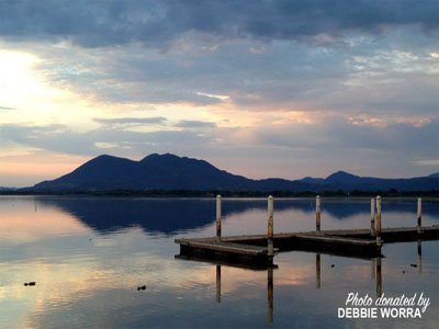 looking past two empty boat docks and across the lake at the hills at sunset. 