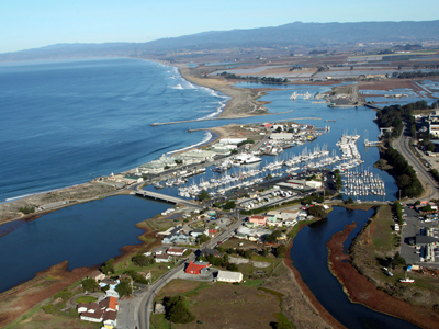 Looking down on the Town of Moss Landing N and S Harbors, the pacific ocean to the left and hills in the background