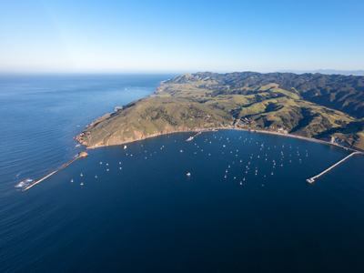 Lookng down on the Port of San Luis on a clear and cloudless day. Boats dot the harbor with green hills behind to the right. 