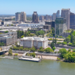 Aerial view of Sacramento on a clear and sunny summer day. The golden Tower Bridge is on the left in the foreground over the Sacramento river, behind is downtown Sacramento.