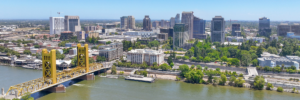 Aerial view of Sacramento on a clear and sunny summer day. The golden Tower Bridge is on the left in the foreground over the Sacramento river, behind is downtown Sacramento.