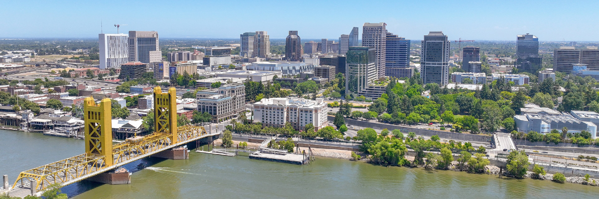 Aerial view of Sacramento on a clear and sunny summer day. The golden Tower Bridge is on the left in the foreground over the Sacramento river, behind is downtown Sacramento.