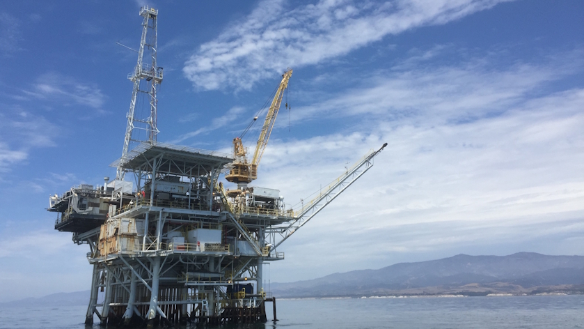 View of Platform Holly from the water on a partly cloudy day with a hill in the background.