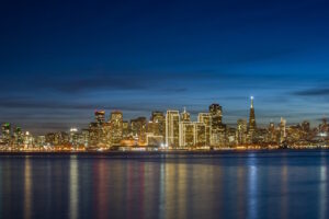 Thousands of lights from the San Francisco skyline reflect on San Francisco Bay.