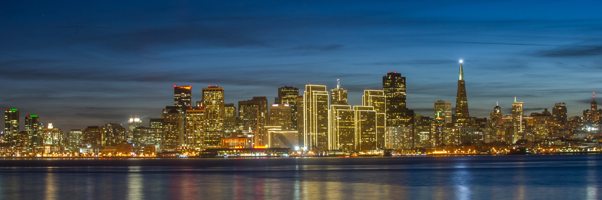 Thousands of lights from the San Francisco skyline reflect on San Francisco Bay.